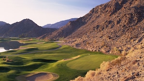 A golf course with a water hazard, surrounded by rocky terrain and mountains. - Mountain Views! Mountains, Palms & Blue Skies, Pet Friendly! - Upstairs w/Garage (L56-2) (La Quinta)