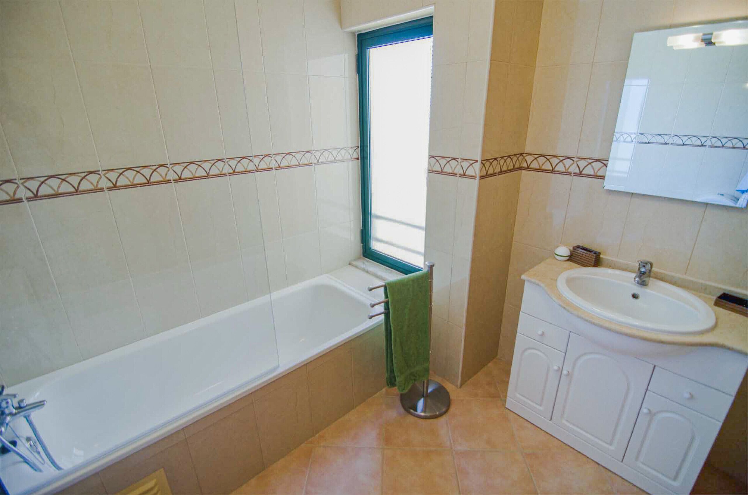 Une salle de bain avec une baignoire, un lavabo et une fenêtre.