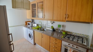 Een keuken met houten kasten, een wasmachine, een fornuis en een spoelbak.