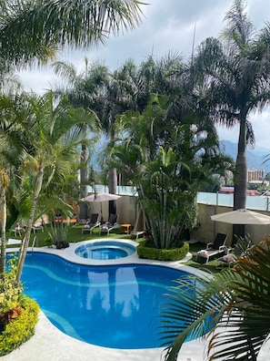 A pool surrounded by palm trees and lounge chairs. - NEQUI HOTEL BOUTIQUE (Tepoztlán)