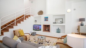 Un salon moderne doté d’un escalier, d’un téléviseur à écran plat, d’une cheminée et d’un coin repas.
