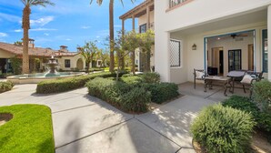 A courtyard with a fountain, palm trees, and a seating area with outdoor furniture.