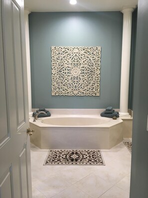 Une salle de bain avec une baignoire sur pieds, un élément décoratif mural et un tapis à motifs.