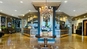 A lobby with a central round table, a chandelier, and a reception desk with floral arrangements. - Hotel Barcelona (Ponta Pora)