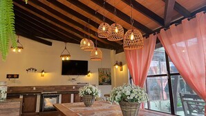 A kitchen with wooden cabinets, a large island, hanging wicker light fixtures, and a window with a view of the outdoors. - Hotel Barcelona (Ponta Pora)
