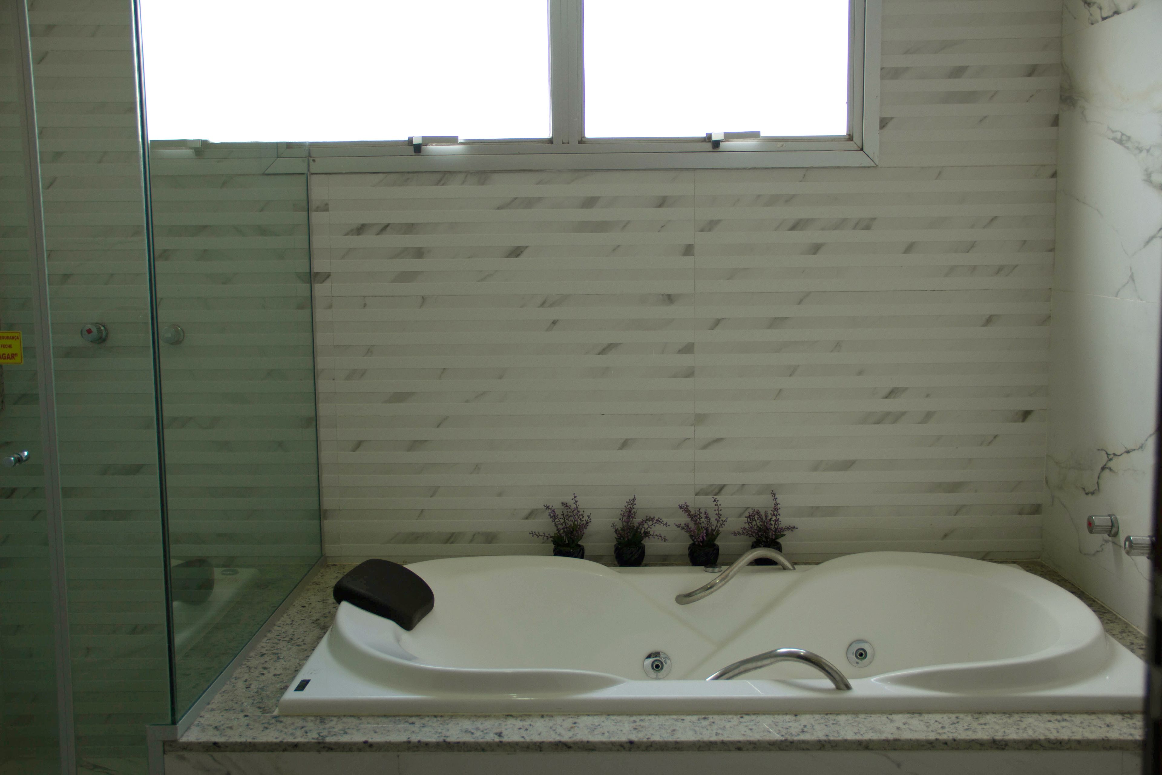 Un baño con cabina de ducha de vidrio, una bañera independiente y una ventana sobre la bañera.