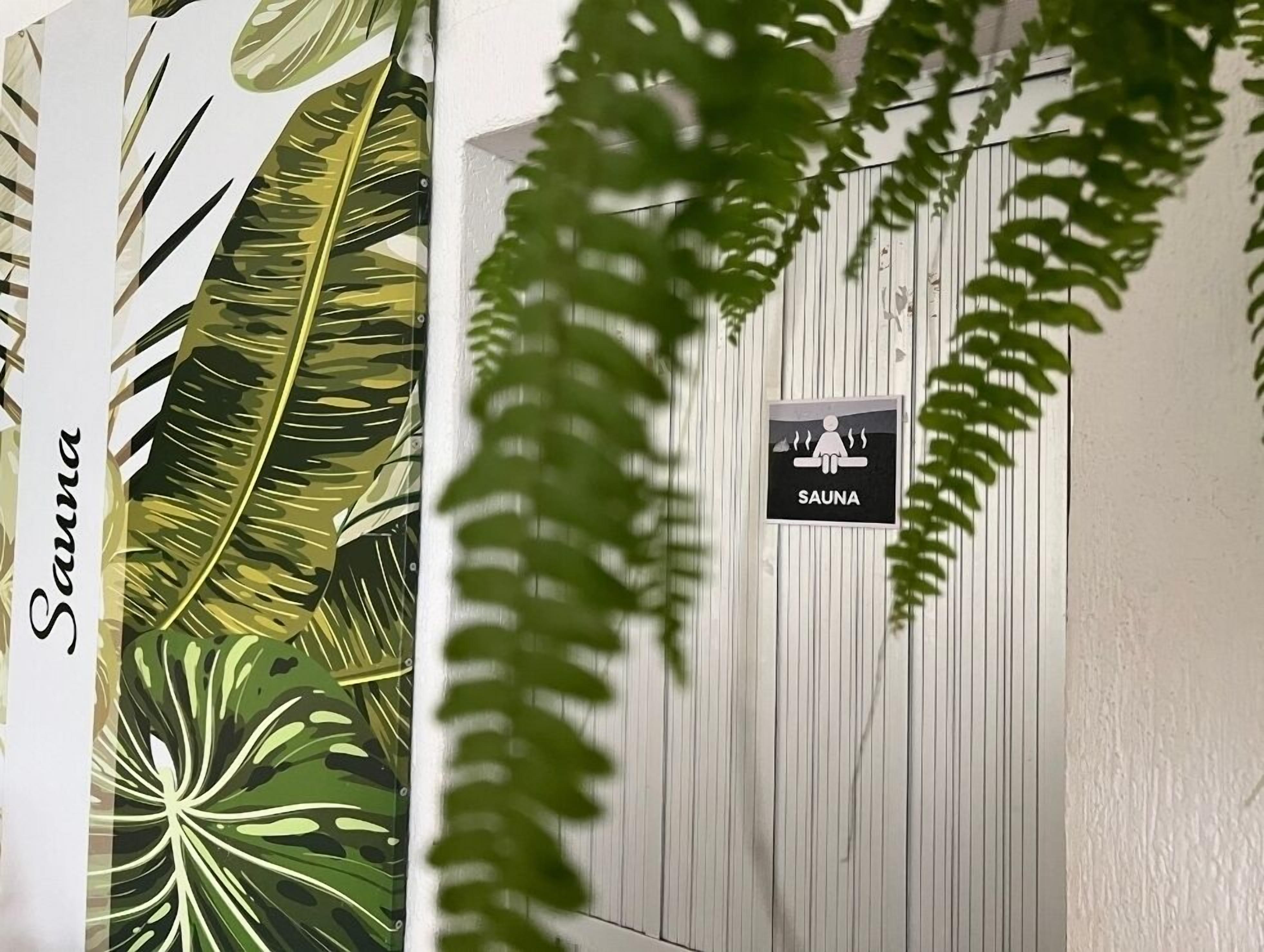 A spa sign on a white wooden wall with tropical leaf patterns on the left.