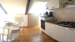 A compact kitchen with a gas stove, white cabinets, and a dining area with a table and chairs.