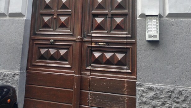 A large wooden double door with diamond patterns, a small plaque above it, and a number '326' on the wall to the right.