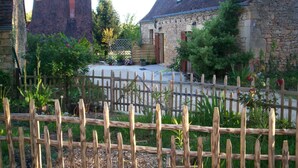 A courtyard with stone buildings, a wooden fence, and potted plants.