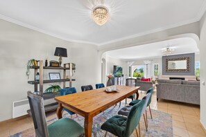 Een ruime woonruimte met een houten eettafel, zithoek en een moderne kroonluchter.