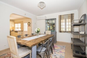 Zona pranzo con tavolo in legno, sedie in metallo, un vaso con fiori e un lampadario.