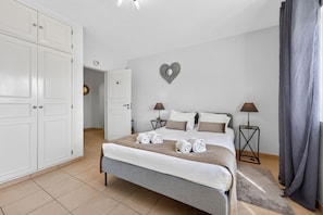 Una habitación de hotel con una cama, dos mesitas de noche, un armario y una decoración en forma de corazón en la pared.