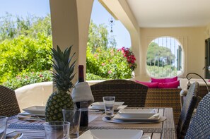 Une table dressée pour le repas, avec des assiettes, des verres et une bouteille, donnant sur une végétation luxuriante.
