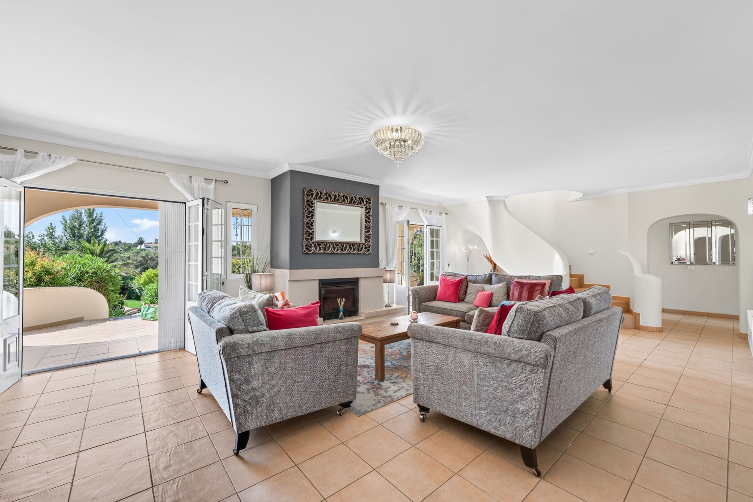 A spacious living room with a fireplace, two sofas, a coffee table, and a chandelier.
