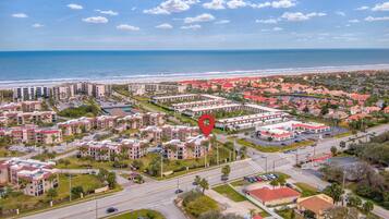 An aerial view of a coastal residential area with multiple apartment buildings, a marina, and a beach.