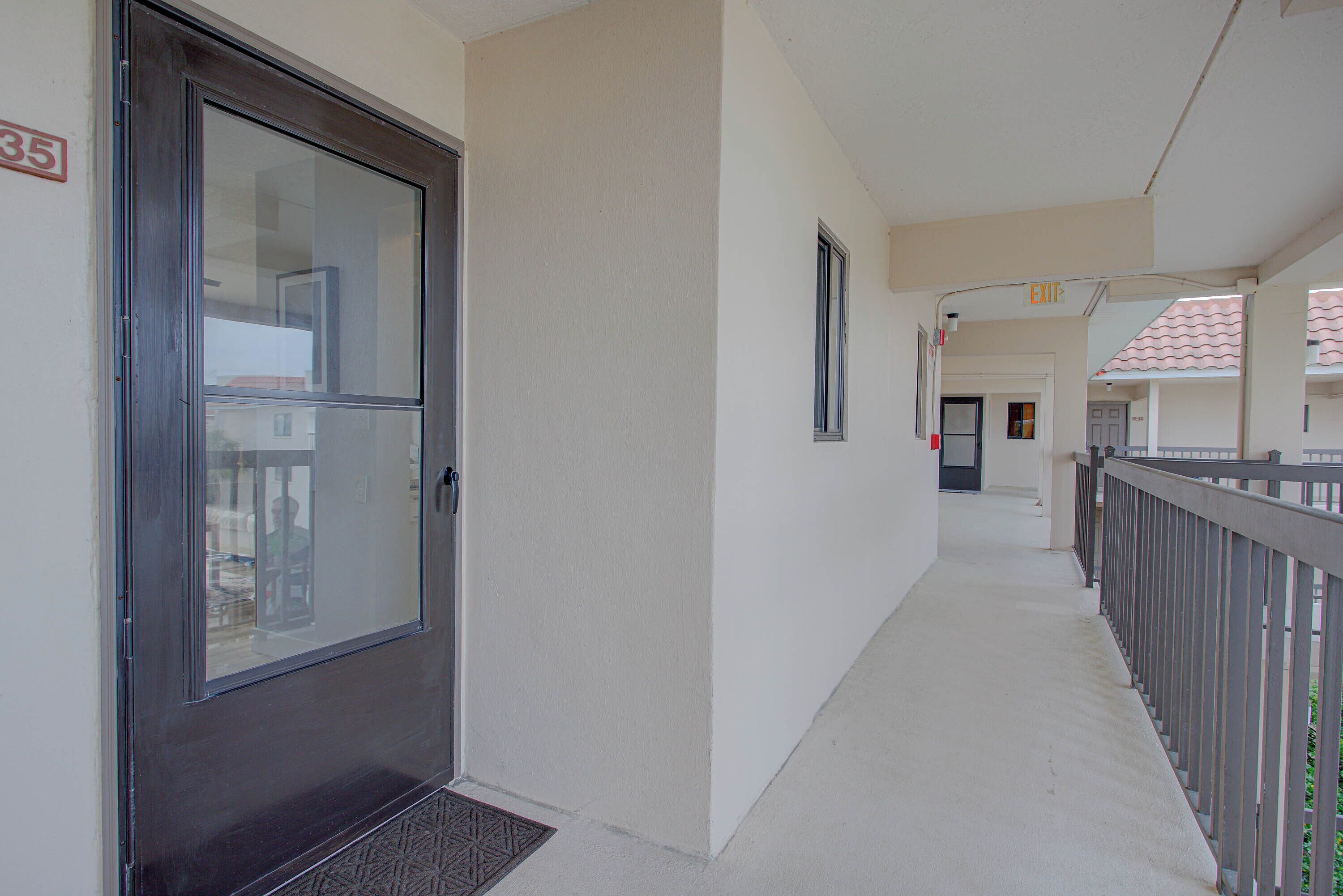 A corridor with a door, a window, and a balcony railing.