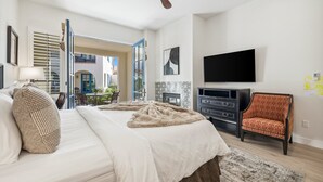 A bedroom with a bed, a chair, a TV, and a ceiling fan.