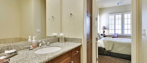 A bathroom with a granite countertop sink, a large mirror, and wooden cabinets.