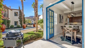 A patio with a grill, a dining area with a table and chairs, and a pool in the background. - Newly Renovated Luxurious Villa with Fountain View, Pet Friendly! - Ground Floor (T21-2) (La Quinta)