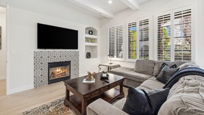 A modern living room with a fireplace, a large flat-screen TV, and a sofa. - Newly Renovated Luxurious Villa with Fountain View, Pet Friendly! - Ground Floor (T21-2) (La Quinta)