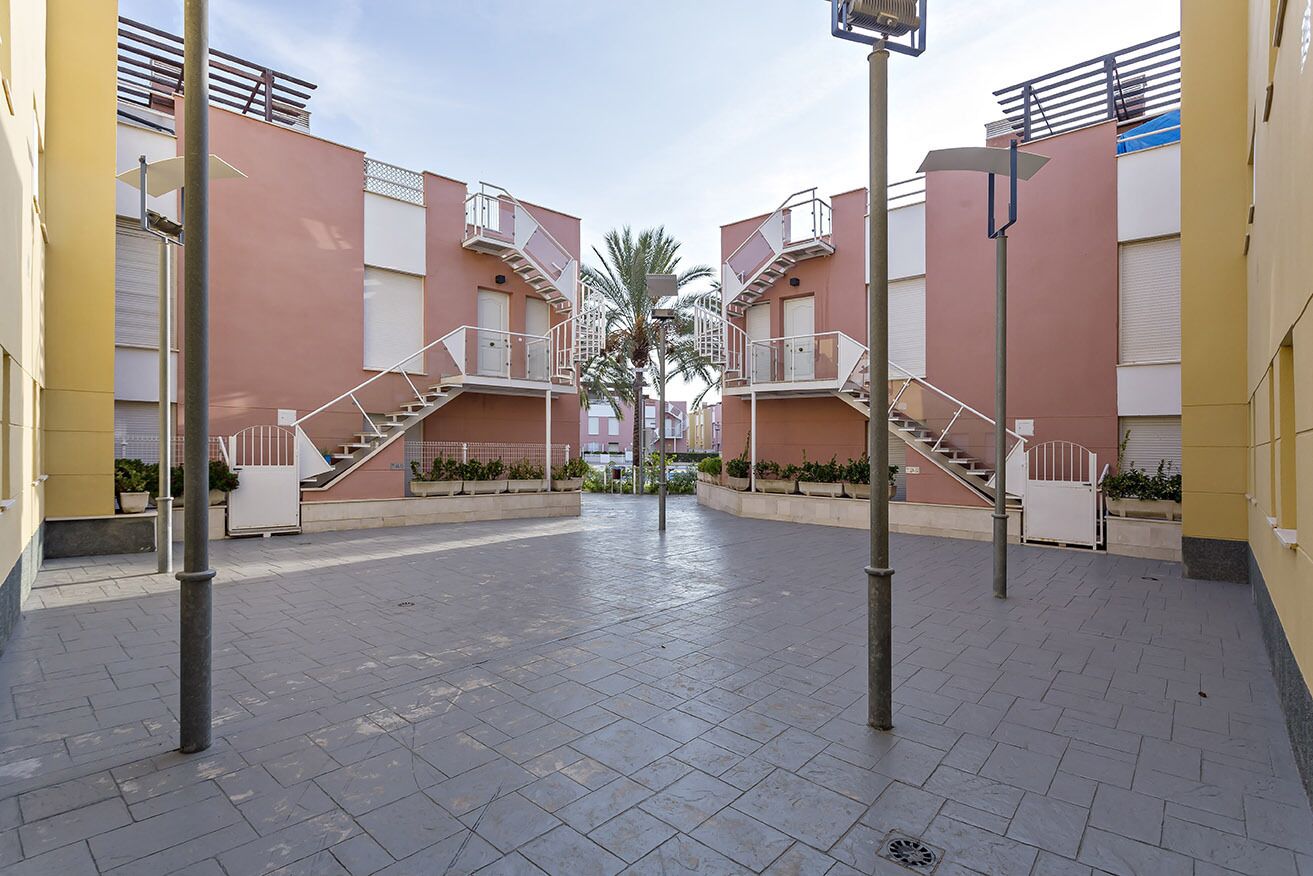 Un patio con una escalera central que conduce a un edificio con balcones.
