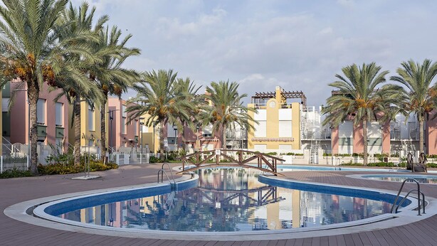 A swimming pool surrounded by palm trees and buildings with balconies. - The Best Condo in Vera with a fantastic View (Vera)