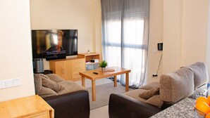 A living room with a TV, sofa, coffee table, and a small plant. - The Best Condo in Vera with a fantastic View (Vera)