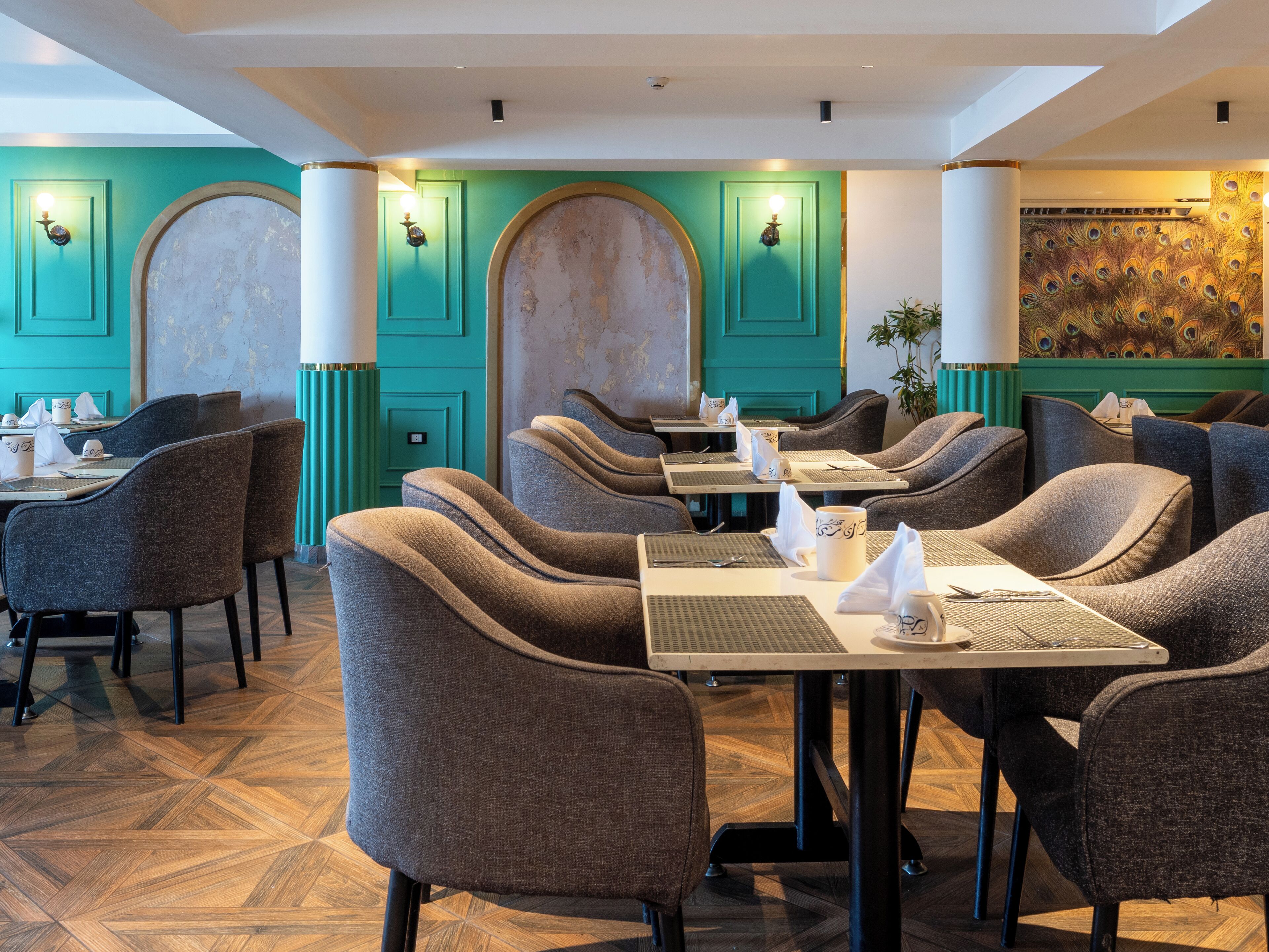 A restaurant with teal walls, wooden floors, and modern furniture.
