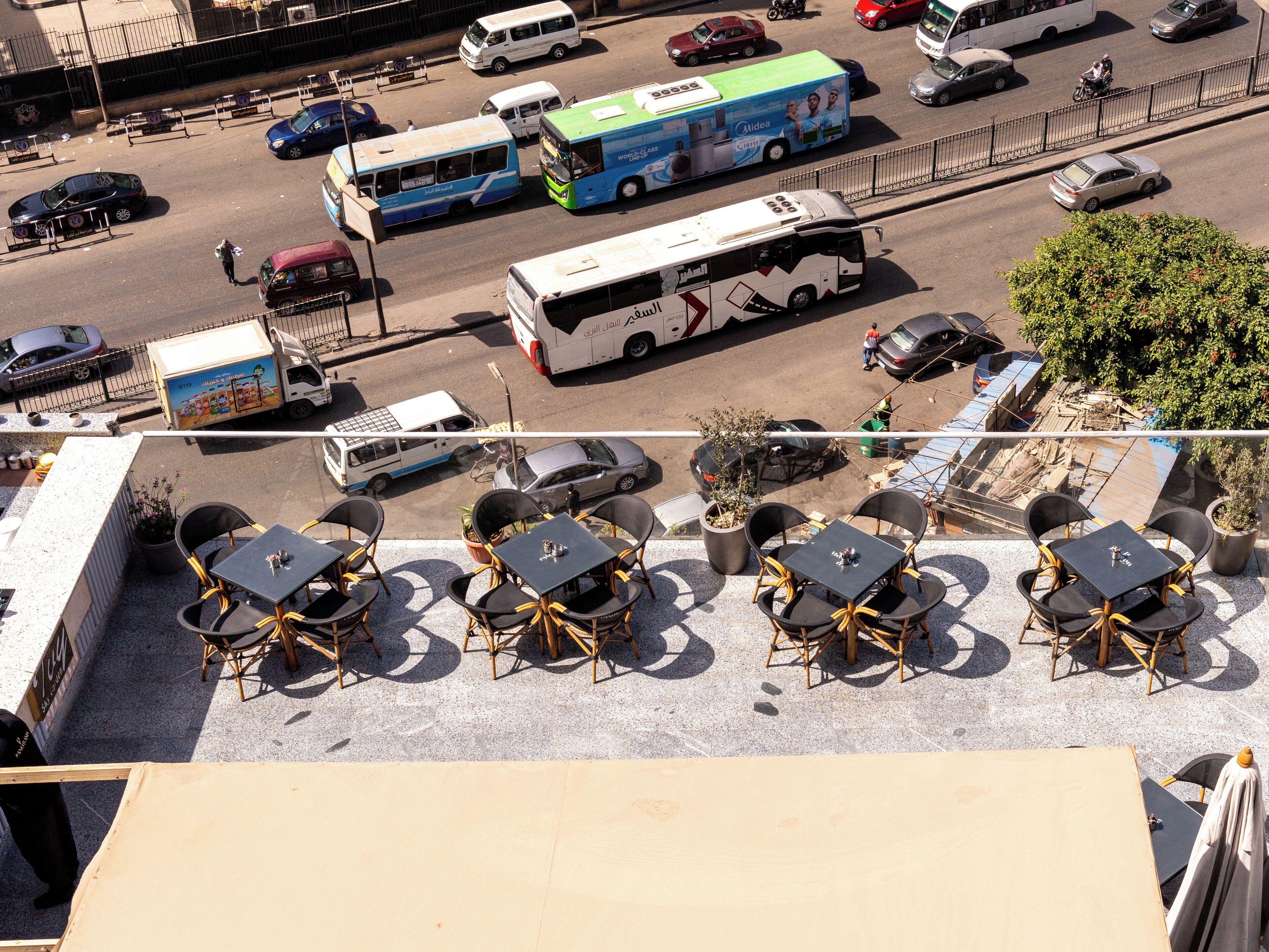 A rooftop terrace with outdoor seating and a view of the street below.