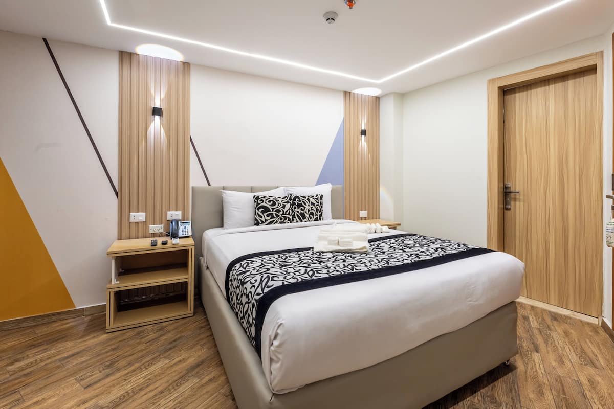 Una habitación de hotel moderna con cama, mesita de noche y armario.