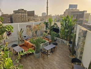 Une terrasse sur le toit, aménagée avec des sièges, des plantes en pot et offrant une vue sur le panorama urbain.
