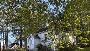 A house with a porch, surrounded by a fenced yard and trees.