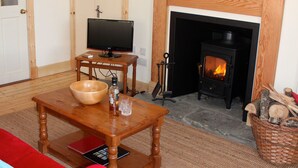 A cozy living room with a fireplace, a television, and a large painting of a Highland cow.