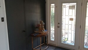 Una puerta de madera con un letrero que dice 'WELCOME', una mesita con un objeto decorativo y un felpudo en la entrada.