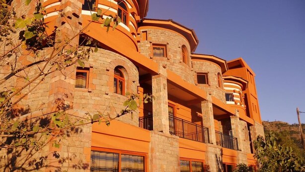 Un edificio de varios pisos con un diseño arquitectónico único, que presenta balcones curvos y grandes ventanales.