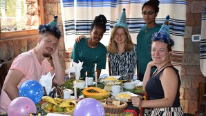 Un grupo de personas en una fiesta con una mesa llena de comida y bebidas.