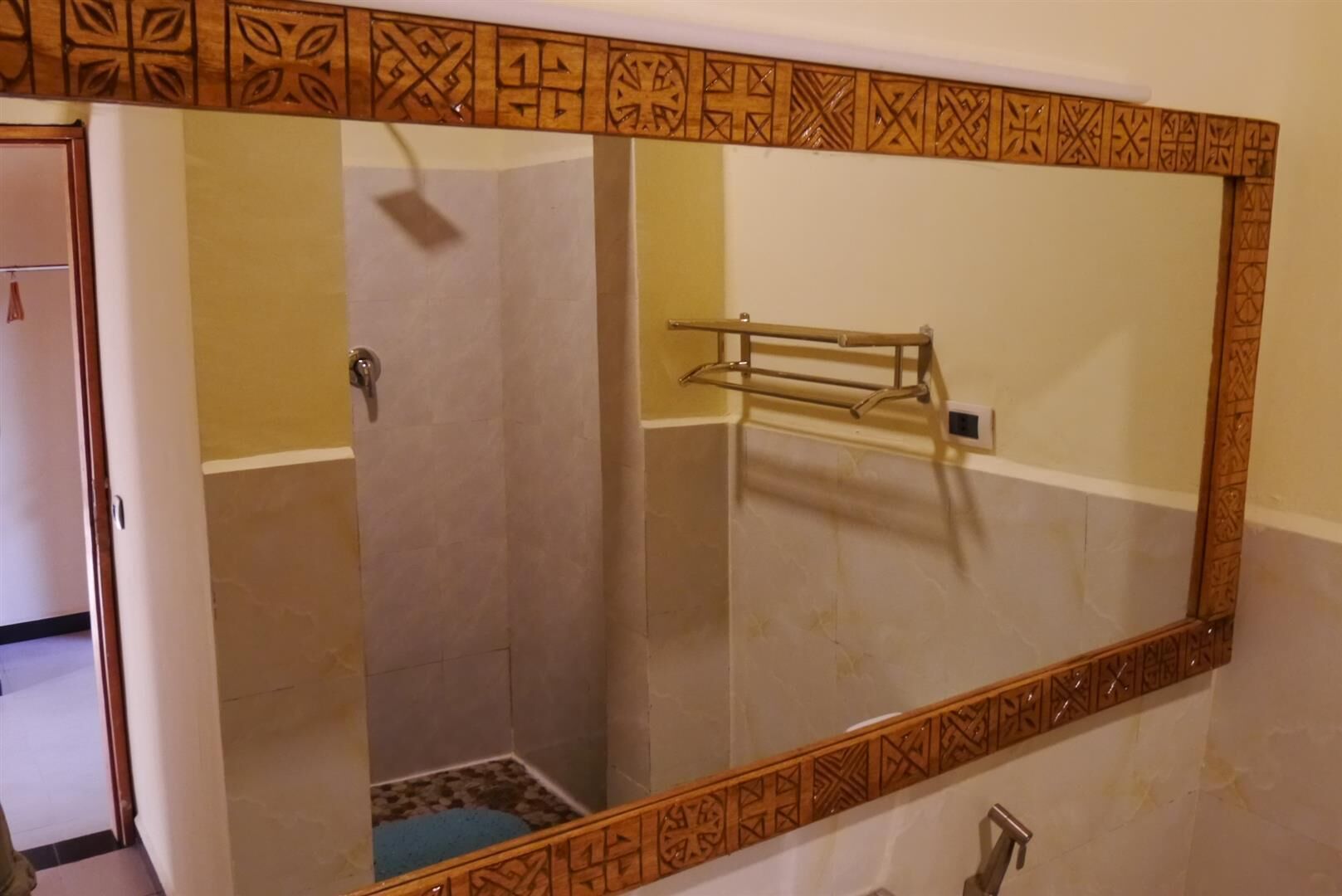 Une salle de bain avec un grand miroir, un porte-serviettes et une porte de douche.