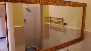 Une salle de bain avec un grand miroir, un porte-serviettes et une porte de douche.