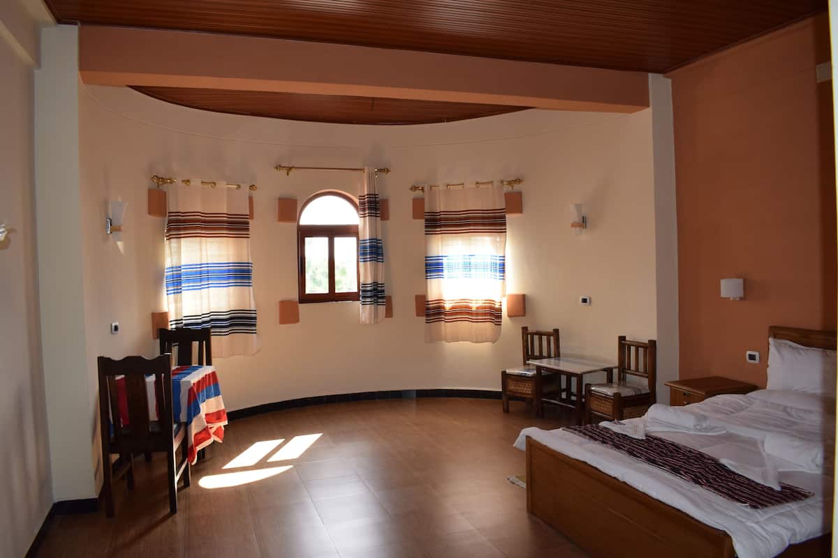 A bedroom with a curved ceiling, a bed, a desk, and two chairs.