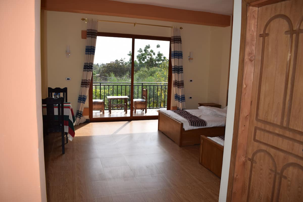 A bedroom with a balcony, a bed, a chair, and a table.
