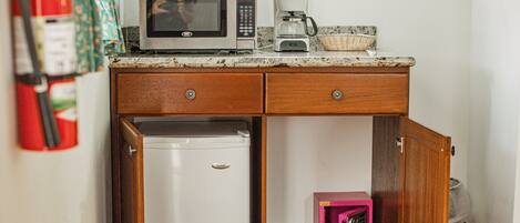 A compact kitchen with a microwave, coffee maker, and a small refrigerator.