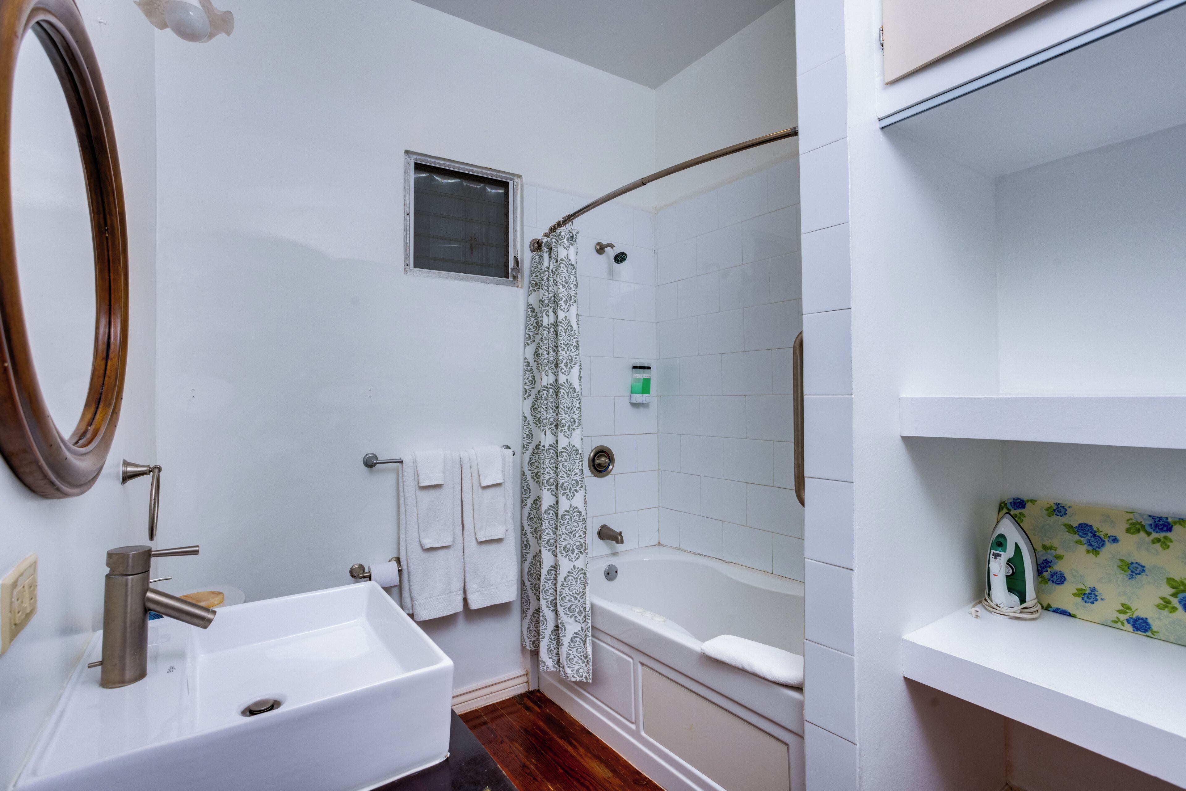 A bathroom with a white sink, a mirror, a shower with a curtain, and a bathtub.