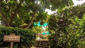Un sendero conduce a una zona de estar con un cartel que dice: "Los árboles son poemas que la tierra escribe en el cielo." 