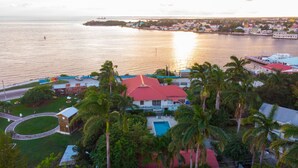 Un pueblo costero con un edificio destacado de techo rojo, un puerto deportivo con barcos y una vista despejada del mar.