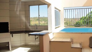 A kitchen with a window, a sink, and a view of a swimming pool. - Thermas Paradise (Rio Quente)