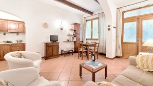 Un salon comprenant un canapé, une table basse, un téléviseur et un coin repas avec des chaises et une table.