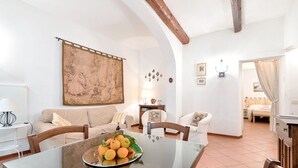 Un coin repas avec une table dressée pour deux personnes, un canapé et un grand tableau accroché au mur.