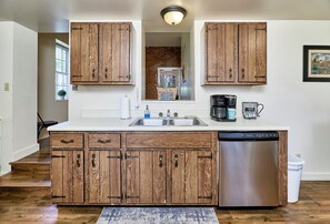 A kitchen with wooden cabinets, a stainless steel dishwasher, and a coffee maker.