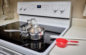 A kitchen with a stove, a pot, a red measuring cup, and a glass jar. - St. Charles 1860's Gem - Sleeps 6! (St Charles)